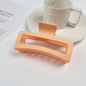 Detailed view of an orange matte square hair claw clip on a minimalist magazine background