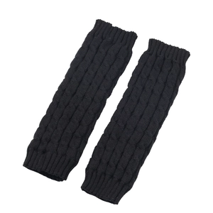 Detail of black cable-knit leg warmers showing thick textured yarn and soft braided pattern