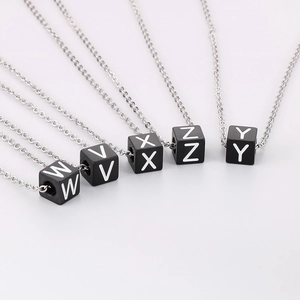 Détail de chaînes argentées avec pendentifs cubes noirs et lettres blanches W V X Z Y