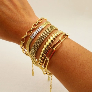 Close-up of stacked gold-plated bracelets including snake, rope, and paperclip chain styles