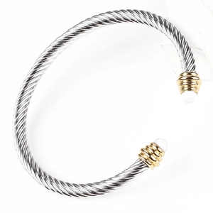 Detail of twisted cable steel bangle with gold accents and pearl inlay terminals