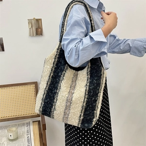 Detail of black and white striped plush tote bag with cozy sheepskin texture