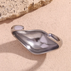 Close-up of a silver polished irregular curved cuff bracelet on a natural stone surface