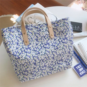 Detail of floral tote bag showing khaki leather handles and gold rivet reinforcement