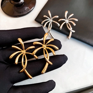Macro shot of gold and silver palm tree earrings with high-shine polished metallic finish
