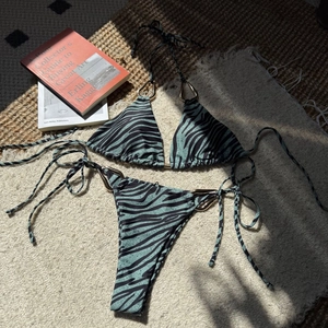 Detailed macro of mint green zebra print bikini featuring gold metal rings and ribbed fabric
