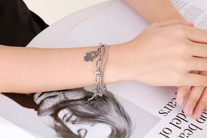 Close-up of double-layered silver Hamsa hand bracelet with heart cutout on a model's wrist