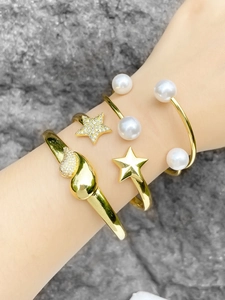 Detail shot of stacked 18k gold plated bracelets with pearls and zircon star patterns