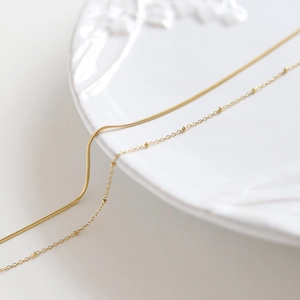 Close-up of 18K gold-plated double-layer snake and satellite chains on white plate