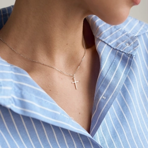 Dettaglio della collana con pendente a croce in acciaio inossidabile su una modella