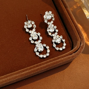 Detailed close-up of silver rhinestone tassel earrings in a luxury brown gift box