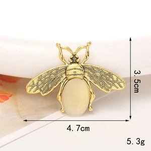 Macro shot of a vintage gold alloy bee charm featuring a yellow gemstone inlay