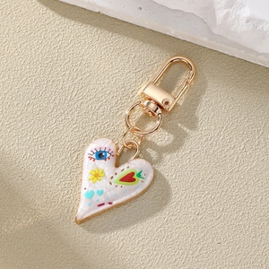 Colorful evil eye heart keychain with floral print and gold plating on textured stone