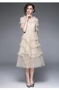 Détail d'une robe en dentelle beige avec volants étagés et boutons en perles fins