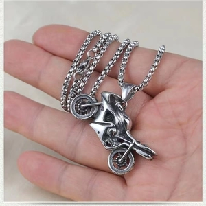 Close-up of vintage silver motorcycle pendant and box chain held in hand