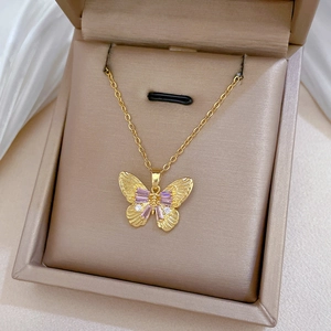 Detailed close-up of a golden butterfly pendant with pink crystals and small white diamonds