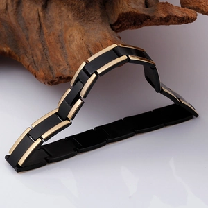 Detail of men's two-tone link bracelet featuring black and gold finish on natural wood
