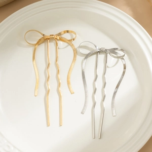 Detail view of gold and silver liquid metal bow hairpins on white ceramic plate