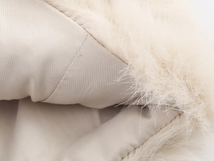 Close-up of white faux fur texture with smooth satin lining and fine stitching detail