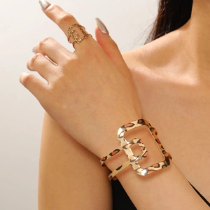 Detalle de brazalete y anillo ajustables dorados con estampado de leopardo y huecos