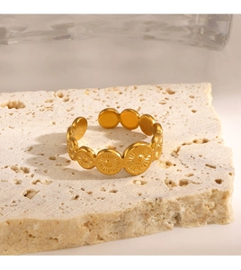 Detailed close-up of a gold sunburst disc ring set on a beige textured stone base