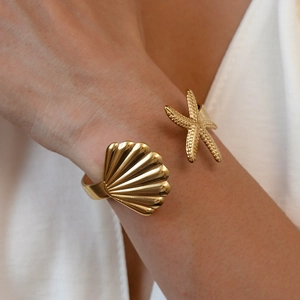 Detail shot of golden starfish and shell open cuff bracelet with polished texture