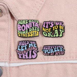 Detail of four creative enamel pins with humorous quotes on a pink denim jacket