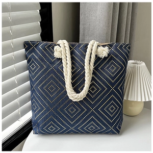 Detail of blue linen tote bag with gold geometric patterns and beige rope handle on desk