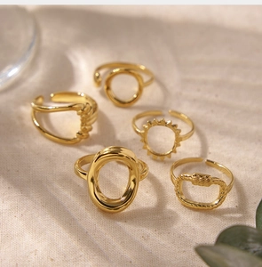 Detailed view of five 18K gold plated twisted and textured open rings on beige fabric