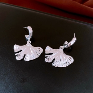Macro shot of silver ginkgo leaf earrings with detailed texture on black background