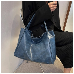 Detail view of large navy blue soft leather tote bag showing drape and spacious capacity
