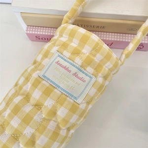 Detail of yellow quilted heart stitching and white fabric label on the plaid cup holder