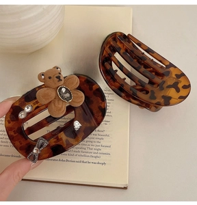 Close-up of tortoise shell hair clip with plush bear and rhinestone bow on vintage book