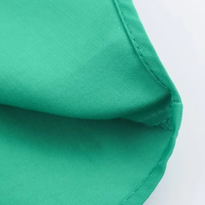 Close-up detail of green satin fabric showing high-quality stitching and smooth texture