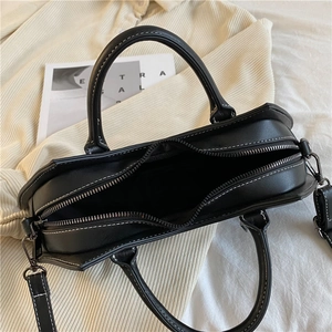 Schwarze PU-Ledertasche mit weißen Kontrastnähten, Tragegriffen und Schulterriemen.