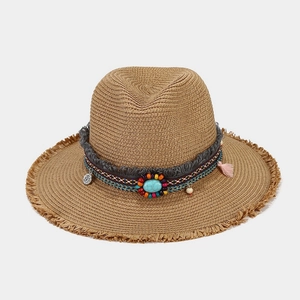 Detail of bohemian straw hat with turquoise beads, woven texture and fringed brim