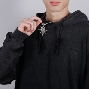 Close-up of a silver sun pendant with a Celtic knot on a twisted chain worn by a model