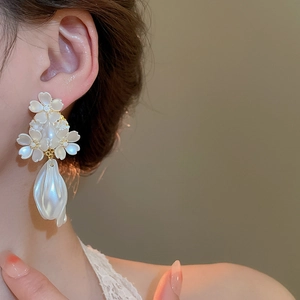 Détail de boucles d'oreilles fleurs avec cerisiers blancs et perle baroque