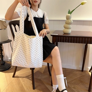 Detailed close-up of a white canvas tote bag with black polka dots in a vintage setting