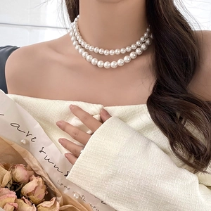 Detail view of layered pearl necklace on collarbone showing elegant aesthetic and luster