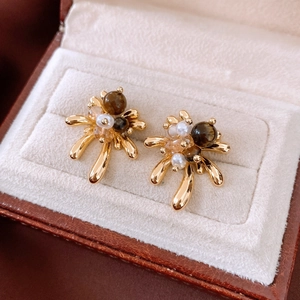 Detail view of vintage 18K gold plated tiger eye stud earrings on a velvet jewelry box