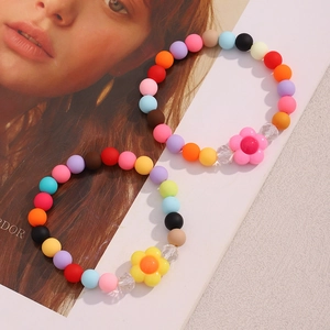 Colorful acrylic beaded bracelets with resin flower charms on a fashion magazine