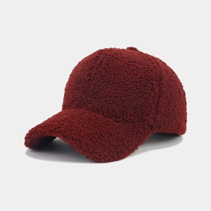 Close-up of deep red sherpa fleece baseball cap showing thick fuzzy texture and curved brim
