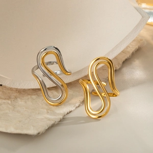 Minimalist irregular S-wave gold and silver rings on white textured stone background