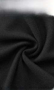 Macro shot of black waffle knit fabric texture showing breathable jacquard details