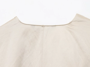 Detaillierte Makroansicht des Rundhalsausschnitts und der feinen Leinenstruktur in Beige