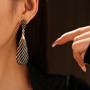Gros plan de boucles d'oreilles vintage noires et dorées avec motif en spirale élégant