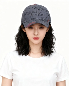 Detail of dark grey baseball cap with graffiti letters and red accents on curved brim