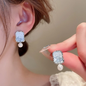 Close-up of silver-trimmed ice-crack crystal earrings with elegant pearl pendant drops