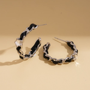 Détail d'une boucle d'oreille en chaîne argentée avec cuir noir et cristal transparent